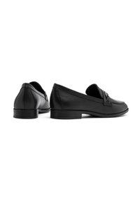 Zwarte leren loafers met een lage hak, voorzien van een gestikt ontwerp en een decoratieve band over de voorkant. Gladde textuur, klassieke vorm.