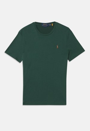Grön kortärmad t-shirt i mjukt tyg med rund hals och en liten broderad logotyp på vänster bröst. Minimalistisk design.