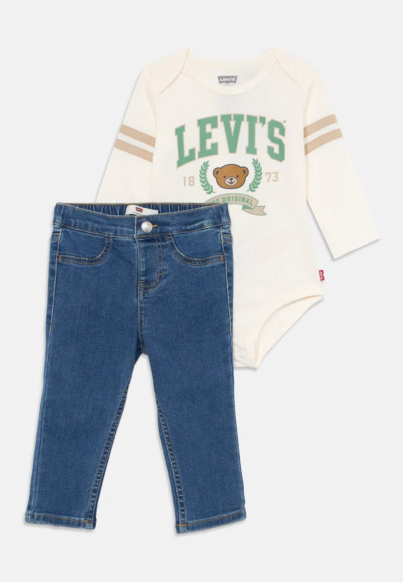 Levi's babykläder som består av en krämfärgad långärmad bodysuit med grön logotyp och beige ränder, i kombination med blå denimbyxor.