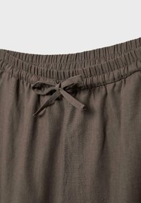 Pantalon à taille élastique en tissu marron foncé avec un nœud de cordon noué au centre devant.