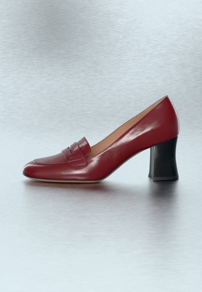 Escarpin femme style mocassin en cuir rouge avec bout arrondi et talon carré, présenté sur une surface réfléchissante gris clair.