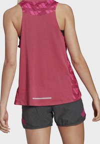 Różowy sportowy top bez rękawów z geometrycznymi wzorami na plecach, zestawiony z szarymi szortami z różowym akcentem. Odblaskowy detal przy krawędzi.