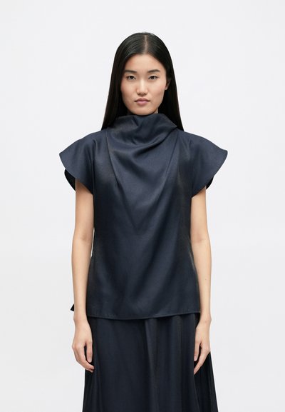 Dark navy blouse with a high folded collar, short cap sleeves, smooth texture, and a relaxed fit. Part of a matching outfit.