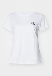 Balta medvilninė marškinė su apvaliu kaklu, trumpomis rankovėmis ir juodu logotipu, kuriame užrašyta "Calvin Klein Jeans" kairėje krūtinėje. Lygus paviršius.