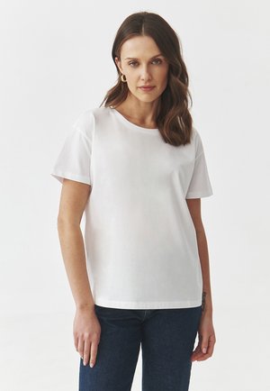 T-shirt blanc à manches courtes en coton doux, avec un col rond et une coupe décontractée. Associé à un jean en denim bleu foncé.