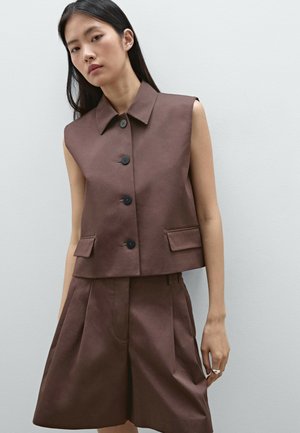 Veste sans manches marron avec un col, des boutons sur le devant et deux poches latérales, assortie à un short marron. Texture de tissu lisse.