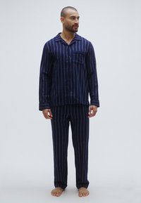 Granatowe pasiasty piżama z miękkiej tkaniny; koszula z guzikami i kieszenią, długimi rękawami oraz pasujące spodnie o prostych nogawkach.