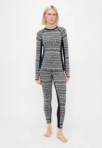 Thermal leggings and top set in patterned black and white, featuring long sleeves and a snug fit with solid black side panel accents.