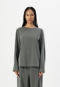 Langermet, crew-neck topp i mørkegrå med vertikale hvite striper. Mykt stoff med en jevn struktur og svakt utsvingte mansjetter.