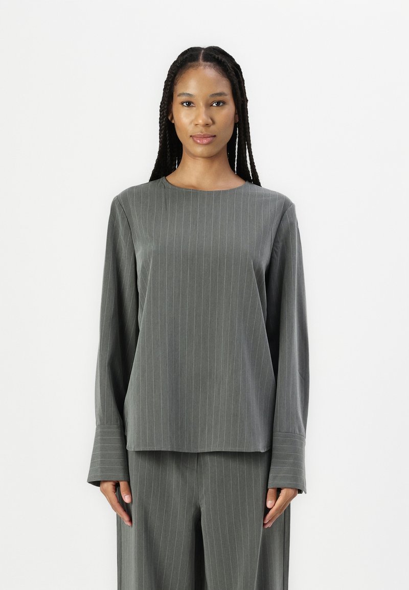 Langermet, crew-neck topp i mørkegrå med vertikale hvite striper. Mykt stoff med en jevn struktur og svakt utsvingte mansjetter.