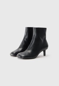 Stivaletti neri in pelle con punta affusolata, design aderente, superficie liscia e tacco modesto. Presentano una chiusura centrale con zip.