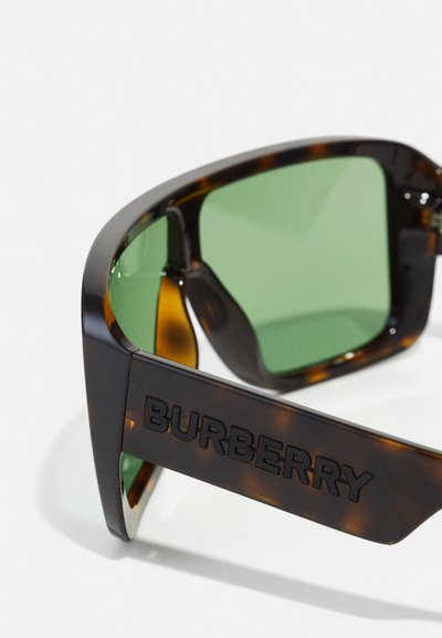 Occhiali da sole Burberry con montatura tartarugata, lenti verdi e unlogo audace sulla stanghetta, caratterizzati da una texture liscia e un design angolare.