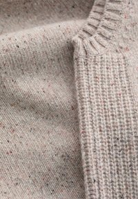Strickpullover aus einem strukturierten, hellbeigen Stoff mit mehrfarbigen Einsprengseln. Rippkragen und glatter Körper mit kontrastierenden Mustern.