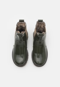 Botas de tobillo de charol verde con forro de piel sintética, paneles laterales elásticos y tiradores. Punta redonda y suela de goma texturizada.