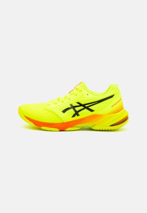 Scarpa sportiva di un brillante giallo con accenti neri, tomaia in rete, superficie testurizzata e un dettaglio arancione sul tallone. Design leggero per prestazioni elevate.