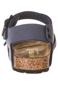 Sandal blu navy con fibbia regolabile, morbido al tatto, con soletta in sughero e suola in gomma. Presenta una parte superiore liscia e due bottoni laterali.