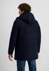 Marine pufferjack met capuchon, voorzien van een horizontaal gestikt patroon, zijzakken en een iets langere achterkant.