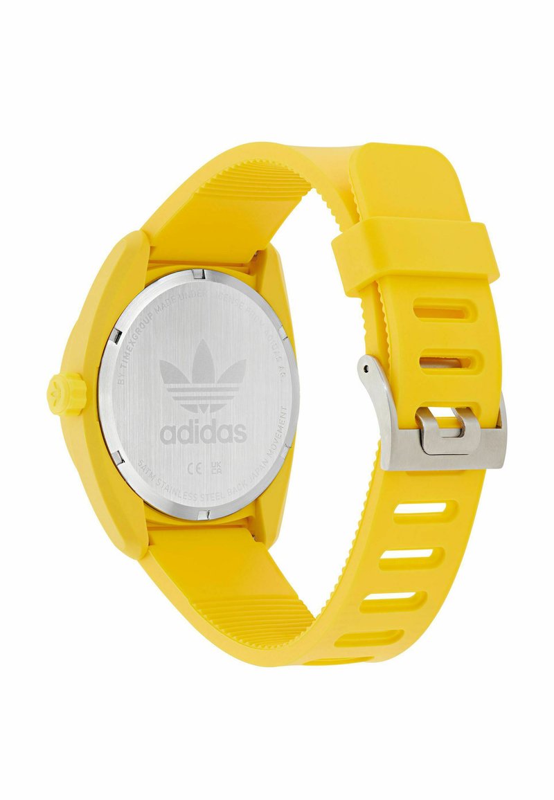 Gele siliconen horloge met een ronde kast, een achterkant van roestvrij staal en zilverkleurige onderdelen. Heeft groeven op het bandje voor textuur.