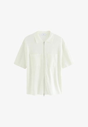 Lühikeste varrukate ja valge lukuga pluus, mis on valmistatud tekstureeritud kangast. Pluusil on kraega kaelus ning kaks eesmist taskut ruudukujuliste klappidega.