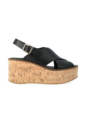 Sandalo platform in pelle nera con tacco a zeppa in sughero, punta aperta, cinturini incrociati e cinturino alla caviglia regolabile con fibbia.