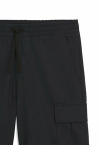Zwarte cargobroek met een elastische tailleband met een trekkoord, zijzak en een textuurstof met een subtiel patroon.