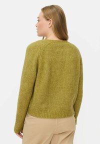 Olijfgroene wollen trui met een losse pasvorm, voorzien van een ribbelzoom en textuur. Gezien van achteren, met details op de schoudernaad.