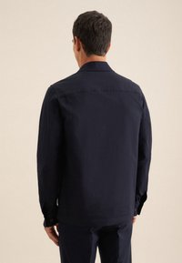 Navyblauwe longsleeve shirt met een kraag, knoopmanchetten, een gladde textuur en een recht gesneden design, waarbij de achterkant wordt getoond.