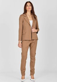 Pruunid triibulised bleiser ja sobivad püksid, valmistatud tekstureeritud kangast. Üksiknupp ja kaks esist pocketit.