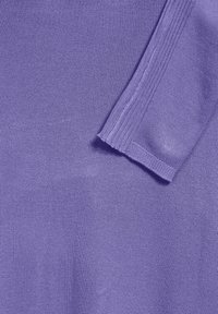 Stickad lila tyg med en jämn textur. Har en ribbad kant på ärmen och ett platt stickat område, enhetligt i färg och mönster.