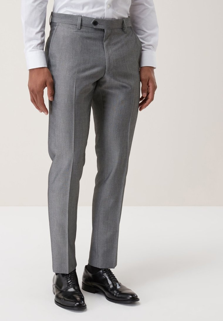 Grau maßgeschneiderte Hose aus glattem Stoff mit geradem Schnitt, seitlichen Taschen und einem Knopfverschluss. Schwarze Anzugschuhe runden den Look ab.