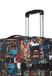 Walizka na kółkach z czarnym materiałem zewnętrznym, ozdobiona kolorowymi wzorami graffiti, z teleskopową rączką oraz bocznym paskiem z klamrą.