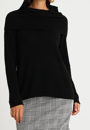 Maglione in misto lana nera con colletto a cascata oversize, caratterizzato da una vestibilità morbida e maniche lunghe, abbinato a una gonna grigia a quadri.