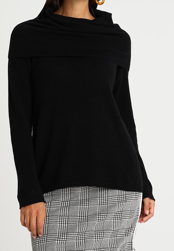Pull en mélange de laine noire avec un col large surdimensionné, offrant une coupe décontractée et des manches longues, associé à une jupe à carreaux grise.
