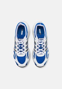 Blå och vita sportskor med en ovandel i mesh, svarta accenter och vita snören. Har en dämpad sula och framträdande varumärke.