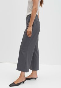 Grijze broek met wijde pijpen en een tailleband op middenhoogte. Gemaakt van een gladde stof, met een nette voorkant en achterkant zonder zichtbare sluitingen of zakken.