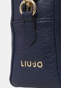 Tamno plava kožna torba s teksturiranom površinom, zlatnim detaljima i istaknutim "LIU•JO" logom sprijeda.