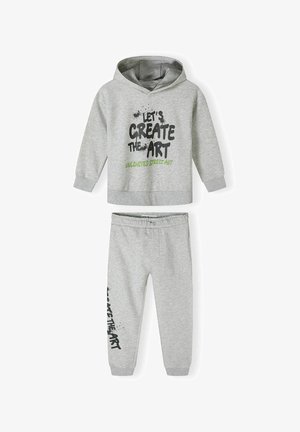 Szürke pamut kapucnis pulóver és nadrág szett. A pulóver grafikus fekete és zöld felirattal rendelkezik. A nadrágon az oldalon illeszkedő szöveges nyomtatás található.