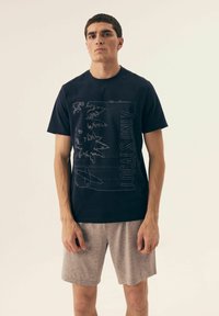 Granatowa koszulka typu crew neck z graficznym nadrukiem palm i surferem. Połączona z jasnoszarymi szortami. Wykonana z miękkiej bawełny.