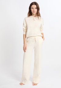 Crème-kleurige loungewear set bestaande uit een hoodie met geribbelde manchetten en joggingsbroek met een elastische tailleband en wijde benen.
