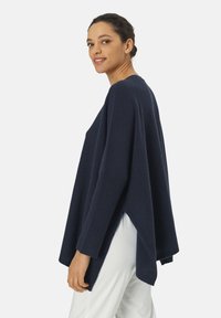 Marineblaues, übergroßes Strickpullover mit asymmetrischem Saum, gerippten Bündchen und weicher Textur. Bietet eine lockere Passform und seitliche Schlitze für zusätzlichen Komfort.
