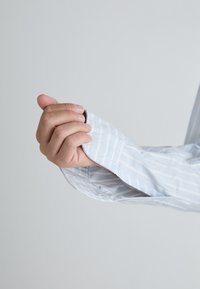 Light blue collared shirt with white stripes, featuring rolled cuffs, a smooth fabric texture, and a button detail visible on the sleeve.