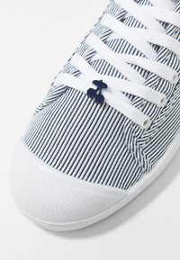 Sneaker in tessuto a righe con suola in gomma bianca, lacci bianchi e un accento con logo ciliegia navy sui lacci.
