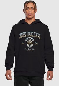 Sort hættetrøje med en frontlomme, snoretr�æk i hætten og metallisk tekstgrafik: "BROOKLYN 16 34 New York City" med et stiliseret 'B'.
