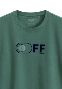 Zielona bawełniana koszulka z okrągłym dekoltem oraz graficznym nadrukiem z napisem "FF" i wzorem z przelotką w granatowym kolorze.