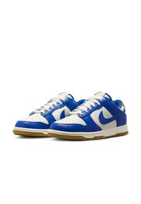 Blue and white leather sneakers with perforated toe, white laces, tan rubber sole, and a blue liner. Features a signature swoosh logo.