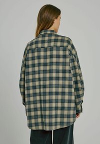 Rutig skjorta i beige och teal med en avslappnad passform, knäppta ärmslut och ryggsömn. Mjuk tyg med rutmönster, rundad nederkant.