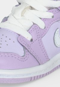 Κοντινό πλάνο σε αθλητικό παπούτσι λεβάντας και λευκό, με λευκά κορδόνια, διάτρητη μύτη και ορατές ραφές στο δερμάτινο επάνω μέρος.