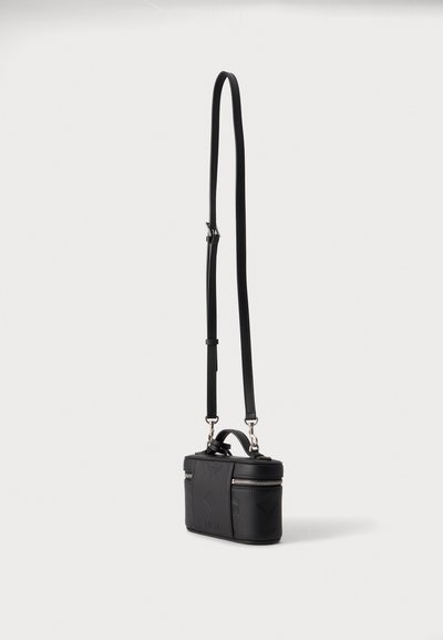 Sac bandoulière rectangulaire noir avec sangle d'épaule ajustable, poignée supérieure et fermeture éclair argentée sur un fond uni.