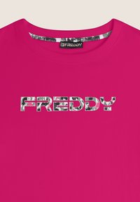T-shirt in cotone rosa con collo rotondo, caratterizzato da un logo riflettente "FREDDY" in testo a pattern argento e nero.