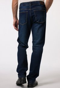 Tmavě modré džíny s volným střihem, elastickým pasem a dvěma zadními kapsami. Tkanina má hladkou texturu a jemné švy.